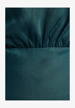 Teal saten tkanina sa glatkom teksturom. Nabran detalj na vrhu i čvrsti panel na dnu stvaraju vizualni interes i dubinu.