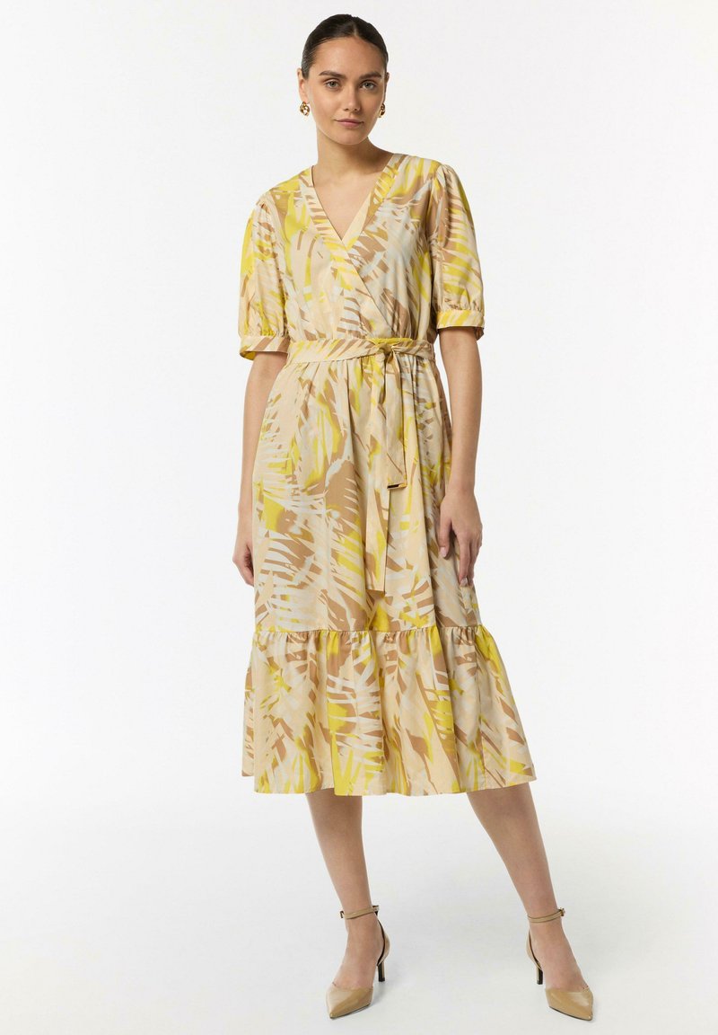 Kleid mit Blumenmuster in Gelb-, Beige- und Hellbrauntönen. V-Ausschnitt, kurze Puffärmel und ein gestufter Rüschensaum. Mit gebundenem Taillendetail.