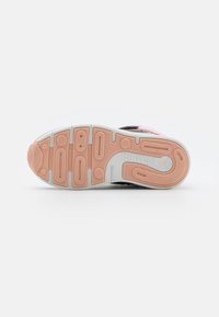 Semelle de chaussure pour enfant en caoutchouc rose et blanc avec une bande de roulement texturée et le nom de la marque "Fruitchi" visible sur la zone du talon.