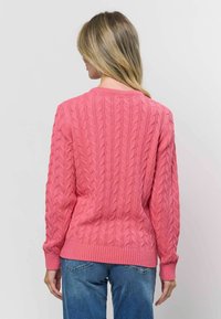 Kabelstrikket sweater i klar pink, med ribbede manchetter og kant. Designet inkluderer et struktureret mønster med rund hals.