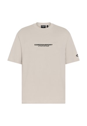 Beiges T-Shirt mit kurzen Ärmeln, mit "CORDONSPORT ATHLETICS 1986" in Schwarz auf der Brust gedruckt und einem kleinen Logo auf dem linken Ärmel.