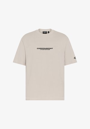 Beiges T-Shirt mit kurzen Ärmeln, mit "CORDONSPORT ATHLETICS 1986" in Schwarz auf der Brust gedruckt und einem kleinen Logo auf dem linken Ärmel.