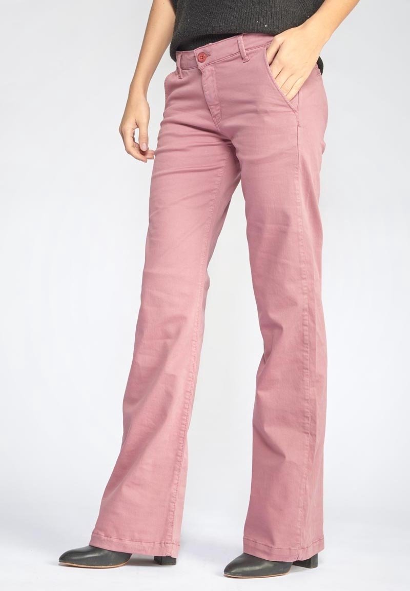 Růžové bavlněné rozšířené kalhoty se zapínáním na zip a knoflík. Disponují předními kapsami a jemnými švy. Noseny s černými vysokými botami.