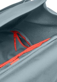 Interno della borsa in tessuto grigio con una texture liscia. Presenta una tasca con zip rossa e un bordo con zip rossa coordinata lungo l'apertura.