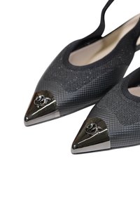 Chaussures noires à bout pointu avec tissu texturé pailleté et accents argentés métalliques, présentant un détail de logo et un design élégant.