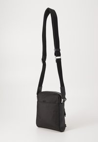 Borsa a tracolla nera realizzata in tessuto resistente; presenta una chiusura superiore con zip, una tracolla regolabile e una finitura liscia e opaca con dettagli minimalisti.