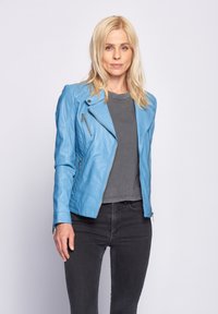 Hellblaue Lederjacke mit asymmetrischem Reißverschluss, gesteppten Schulterdetails und langen Ärmeln, kombiniert mit einem grauen T-Shirt und schwarzen Jeans.