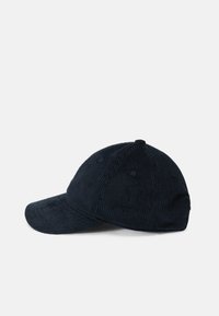 Gorra de béisbol de terciopelo en color azul marino con visera curva, diseño de seis paneles y orificios de ventilación cosidos. Textura suave con patrón de acanalado.