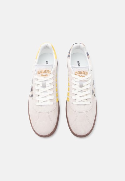Paire de baskets en daim blanc avec des accents jaunes et imprimé léopard, des lacets blancs et la marque "DSQUARED2 Rebels" sur la languette.