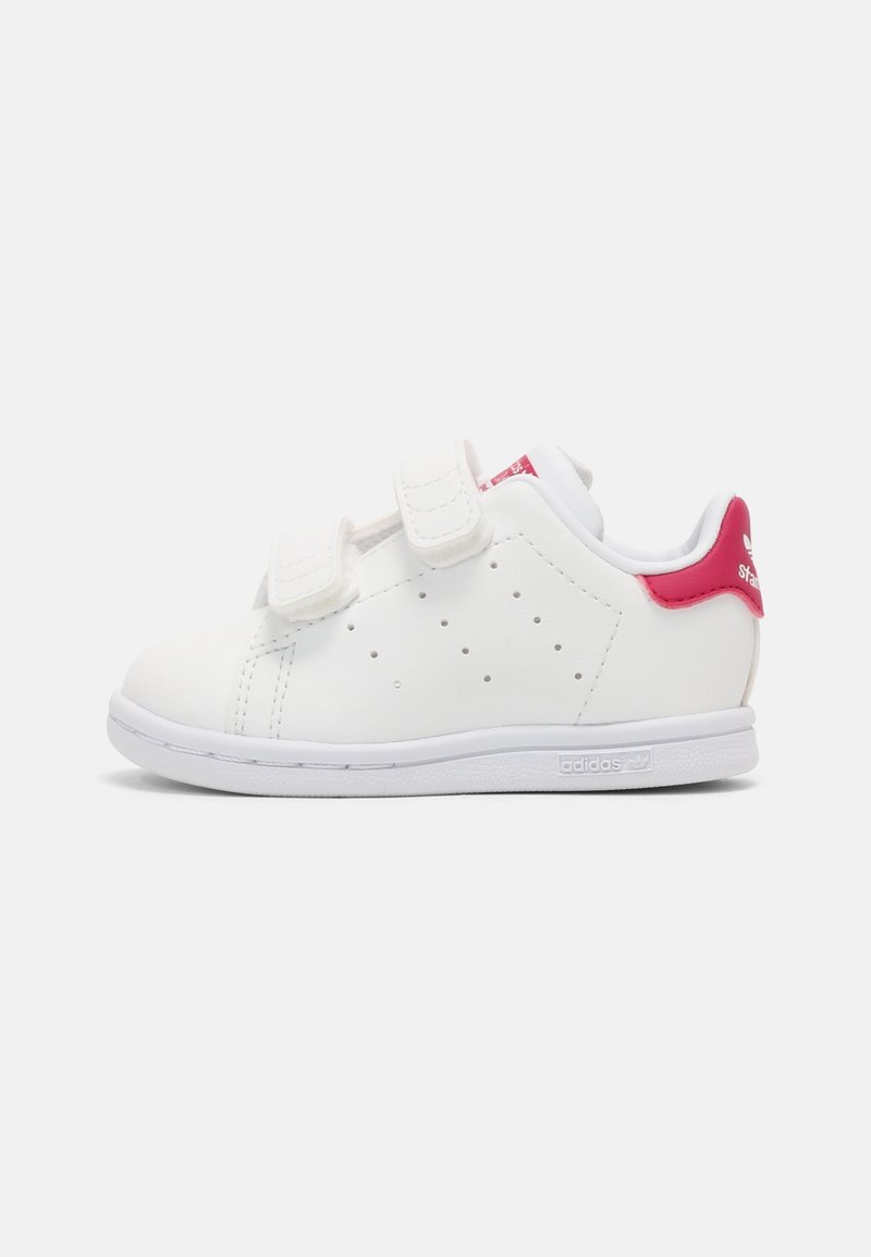 Sneaker bianco in pelle con accenti rosa, caratterizzato da due cinturini con chiusura a strappo, lati perforati e suola in gomma bianca.