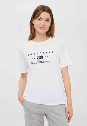 T-shirt bianco in cotone con testo nero "AUSTRALIA 1999 City of Melbourne" e una piccola grafica della bandiera australiana. Maniche corte, fit rilassato.