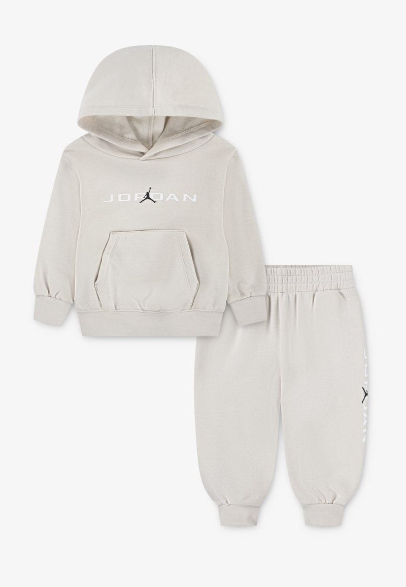 Ljusgrå hoodie och sweatpants-set. Hoodien har en framficka, ribbade ärmar och "JORDAN"-logotyp med en svart Jumpman-grafik.