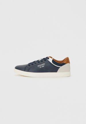 Navy blue leather sneakers with white sole, brown accents, and black laces. Features logo detail on the side and a textured back panel.