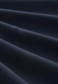 Un tissu bleu marine foncé avec une surface lisse et légèrement texturée, présentant de profonds plis et des lignes horizontales à travers le matériau.