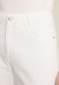 Białe dżinsy z denimu charakteryzujące się klasycznym pięciokieszeniowym designem, metalowym zapięciem na guzik oraz gładką fakturą z subtelnymi detalami szwów.