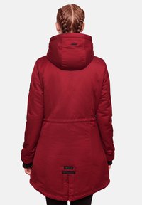 Chaqueta acolchada roja con capucha, que presenta una cintura ceñida, puños elásticos y herrajes en negro en el dobladillo. Textura de tela suave.