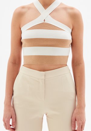 Haut court à rayures avec un motif beige et blanc, texture côtelée, et un design dos-nu avec un détail en forme de trou à l'encolure.