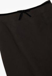 Zwarte rok van gladde stof met een slanke silhouet. Heeft een fluwelen tailleband met een klein strikdetail aan de achterkant.