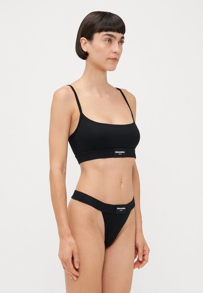 Black underwear set featuring a minimalist design, with a cropped bralette and thong. Made from smooth fabric with logo detailing.