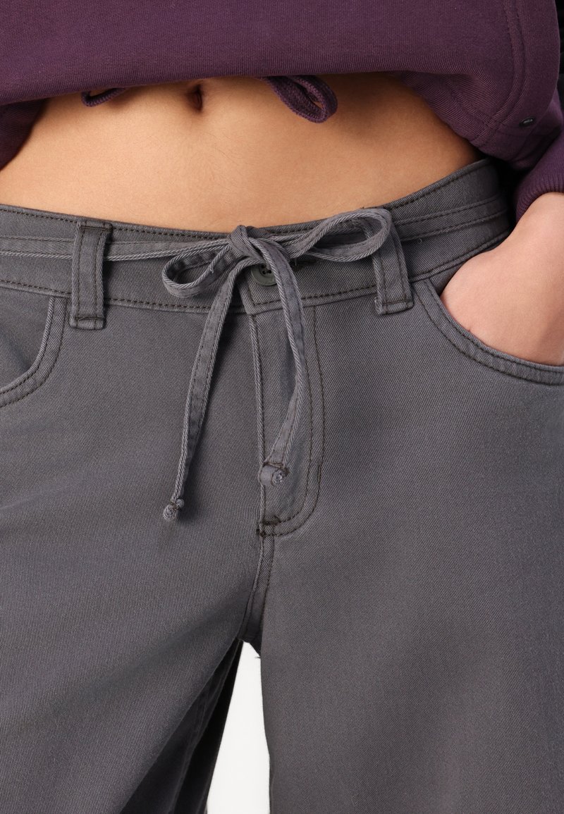 Graue Jogginghose aus einem glatten Material, mit zwei Seitentaschen, einem Knopfverschluss und kontrastierenden Nähten.