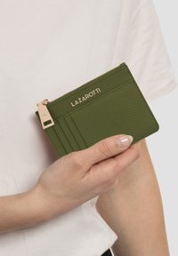 Portafoglio in pelle verde con chiusura zip, cinque scomparti per carte e un accento logo in tonalità dorata. La superficie testurizzata aggiunge dettaglio.