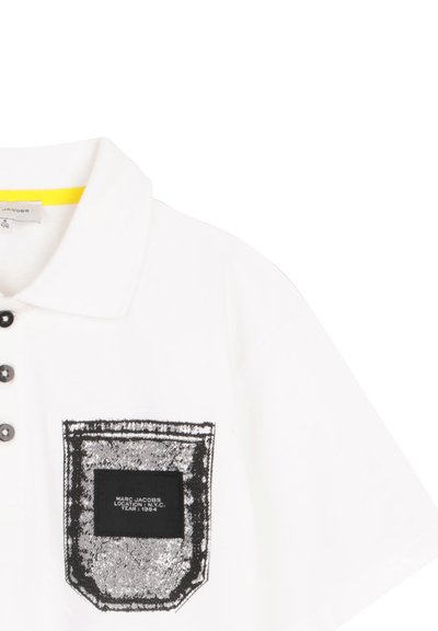 Polo blanc avec boutons noirs et une poche imprimée style denim noir étiquetée "Marc Jacobs Emplacement : N.Y.C. Année : 1984."