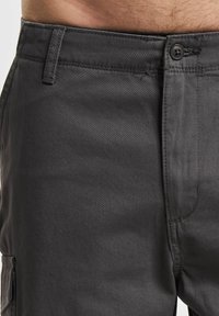 Graue Baumwoll-Cargohosen mit glatter Textur, seitlichen Taschen und Knopfverschluss. Sichtbare Nähte und ein lässiges Design.