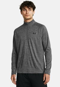 Gray quarter-zip athletic shirt with a subtle striped pattern, long sleeves, and a smooth, flexible fabric. Black logo on the chest.