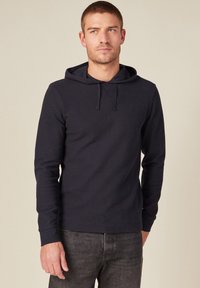 Felpa con cappuccio blu navy a maniche lunghe realizzata in tessuto strutturato, dotata di tasca a marsupio frontale e cordoncino regolabile al collo.