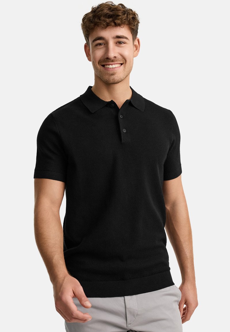 Black polo shirt with a textured knit pattern, featuring a classic collar and three-button placket. Sleeves and hem are ribbed.