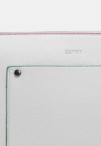 Bolso de cuero blanco texturizado con un detalle de costura verde, que cuenta con un botón a presión plateado y el nombre de la marca "ESPRIT" grabado en la superficie.