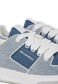 Denim teniske v modri in sivi barvi s belimi vezalkami, z gladko teksturo in blagovno znamko. Trajna gumijasta podplat.