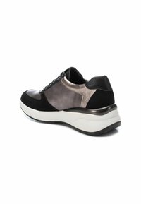 Zapatilla deportiva en negro y gris con detalles en ante y metálicos, forma redondeada, parte superior texturizada y suela acolchada blanca.