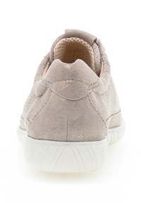 Lichtbeige suède sneaker met een gestructureerde afwerking en een gevoerde kraag. De witte rubberen zool heeft geribbelde details. Subtiele metallic accenten zichtbaar.