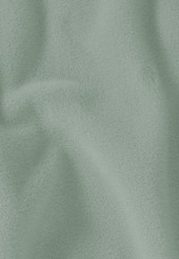 Weicher, mintgrüner Fleece-Stoff mit strukturierter Oberfläche, der ein glattes und leicht flauschiges Aussehen zeigt und sanfte Falten aufweist.