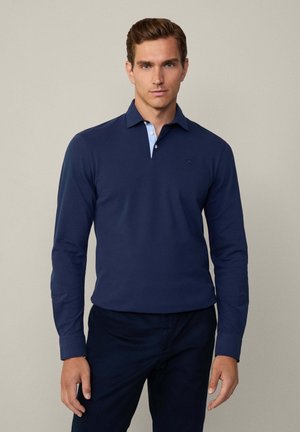 Polo a maniche lunghe di colore blu navy con colletto azzurro chiaro, caratterizzato da un logo discreto sul petto e una superficie del tessuto liscia. Progettato per il comfort.