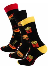 Chaussettes noires ornées de motifs sur le thème de la nourriture : hot-dogs rouges, frites jaunes et burgers. Agrémentées de couvercles rouges et jaunes et de divers motifs imprimés.