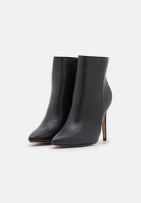 Stivali neri in pelle alla caviglia con punta affilata e tacco alto a stiletto. Finitura liscia con un design elegante e senza hardware visibile.