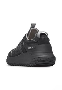Scarpa da atletica nera con upper in suede e mesh, suola testurizzata, collo imbottito e una linguetta posteriore con il marchio "VOLE".