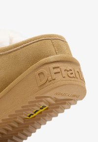 Nærbillede af en tan farvet ruskindsko sål med D.Franklin prægning og struktureret gummisål med gult Vibram-logo.