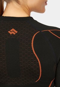 Czarna koszulka sportowa z pomarańczowymi przeszyciami i teksturowanym diamentowym wzorem na plecach. Zawiera logo na górze w centrum.