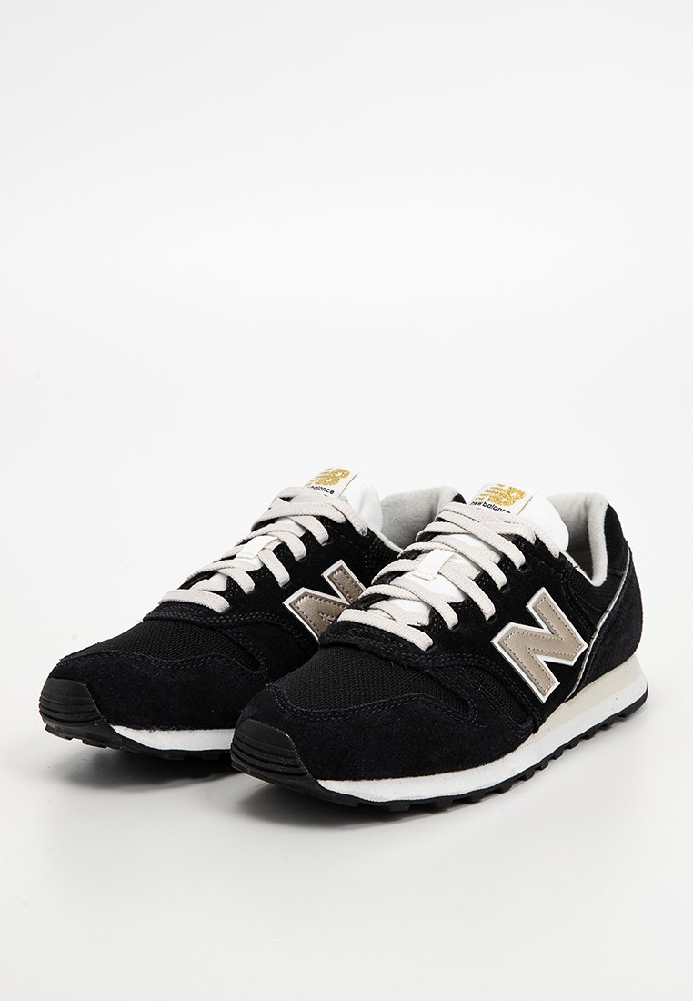 Schwarze Wildledersneaker mit einer weißen Zwischensohle, versehen mit einem hellbraunen New Balance-Logo, Stoffschnürsenkeln und einer strukturierten Zehenkappe.