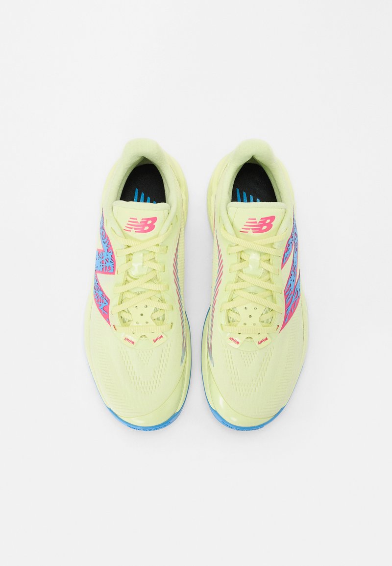 Zapatillas atléticas de color amarillo claro con acentos en rosa y azul, patrones geométricos, diseño de cordones y una parte superior texturizada para mayor agarre.