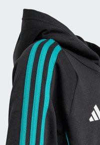 Felpa nera con cappuccio, caratterizzata da un design a tre strisce turchesi sulle maniche e un accento di logo bianco. Materiale morbido, vestibilità rilassata e senza chiusure visibili.