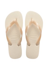 Beige Havaianas papucsok textúrált gumi talppal, kontrasztos barna pántokkal és kis logó részlettel. Kényelmes, hétköznapi viseletre tervezve.
