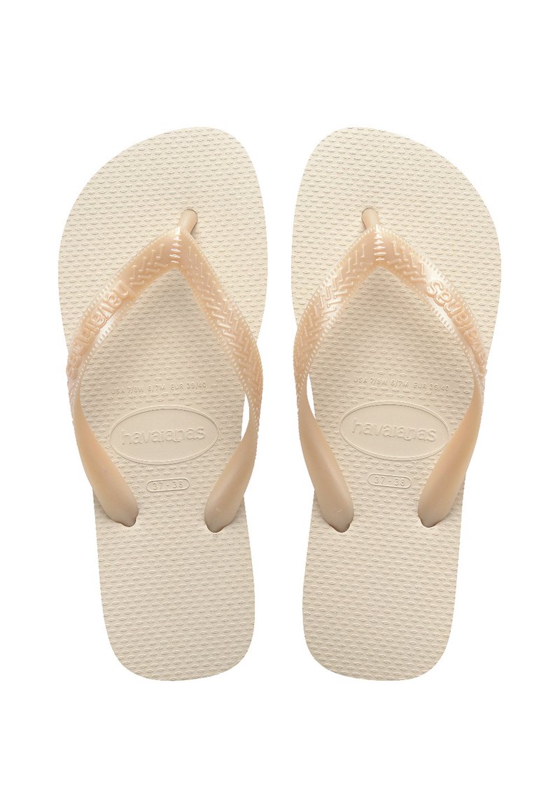 Beige Havaianas papucsok textúrált gumi talppal, kontrasztos barna pántokkal és kis logó részlettel. Kényelmes, hétköznapi viseletre tervezve.