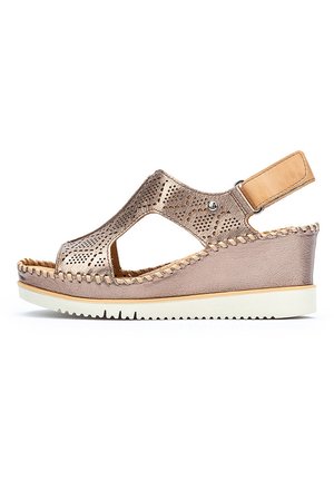 Sandale compensée avec un dessus perforé en métal rose doré, des accents en cuir marron et une semelle en caoutchouc blanc avec un design tressé.