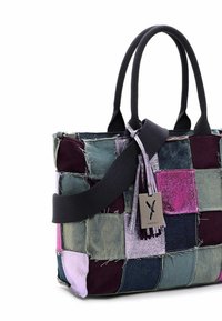 Patchwork tote bag i denim och lila nyanser med svarta handtag, ett brett svart axelband och en silverfärgad varumärkesetikett med fransar.