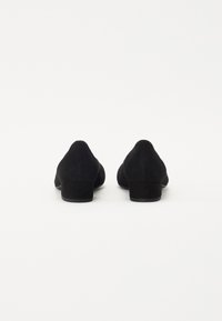 Zapatos de tacón de ante negro con un tacón bajo y cuadrado, punta redondeada y textura lisa, sin adornos ni patrones.