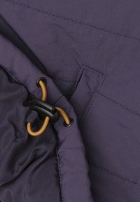 Marineblauwe stof met een gestructureerd oppervlak; heeft een trekkoord sluiting met contrasterend oranje koord en zwarte hardware accenten.